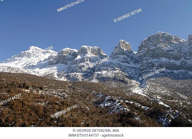 View of Mikro Papingo village and snowy mountains. Mikro Papingo, Ioannina, Epiros, Greece, Europe