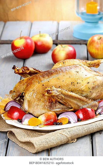 Roasted goose with apples and vegetables on wooden table