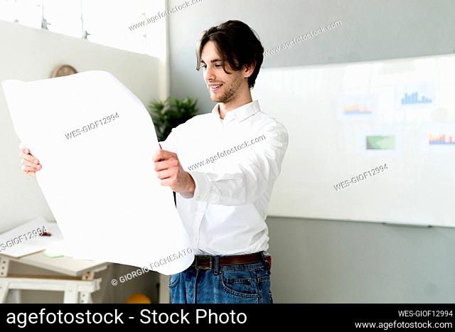 Businessman checking business plan while standing in office