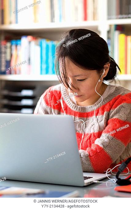 Young Asian woman in casual clothes works at the desk in her home office