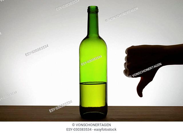 Silhouette of a hand showing thumbs down gesture next to a bottle of wine