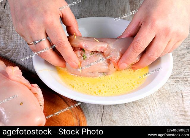 Cooking. A woman's hand dips a stuffed raw chicken breast in an egg. Step-by-step recipe. Stage preparation for cooking dishes. Series