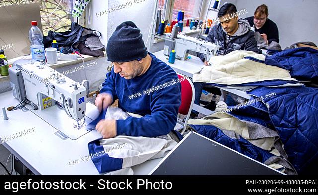 PRODUCTION - 26 January 2023, Mecklenburg-Western Pomerania, Teplitz: Jackets from a collection of the company Nordwolle are sewn by Jaweecsh Abdolkader (front)...