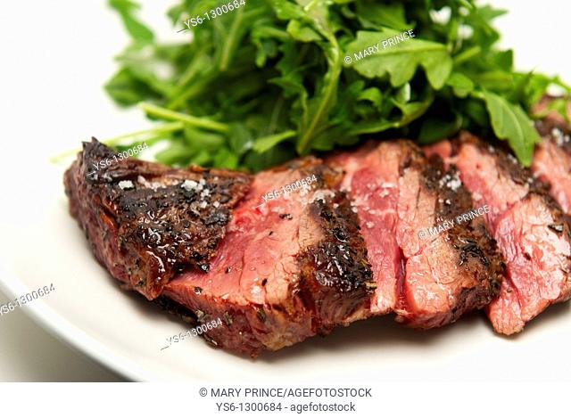Rare Sliced Steak and Arugula on a White Plate
