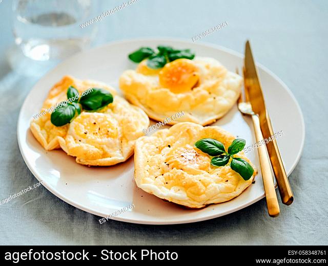 Fluffy Cloud Eggs. Trendy food - oven bake scrambled eggs with whipped egg white and whole yolk on plate