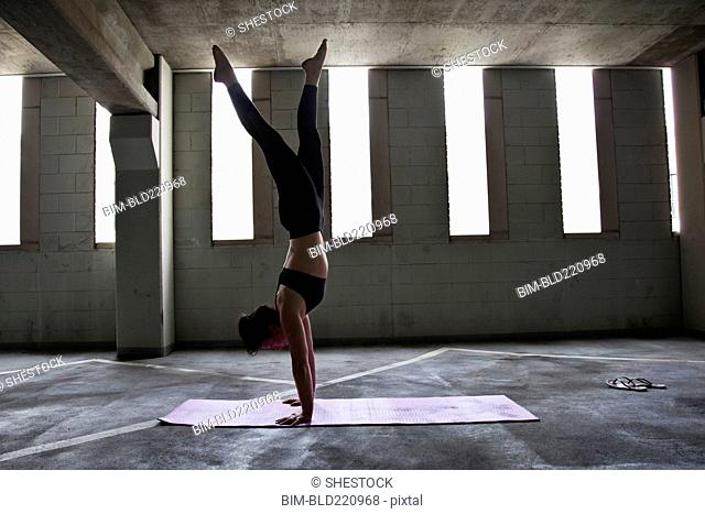 Caucasian woman practicing yoga in parking lot