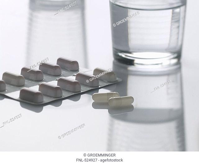 Close-up of capsules in blister pack and glass of water