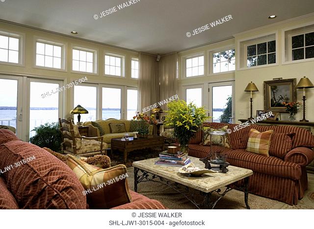 LIVING ROOM: Lake home with view out of wall of french doors and upper square transom windows, french country colors and provincial furniture