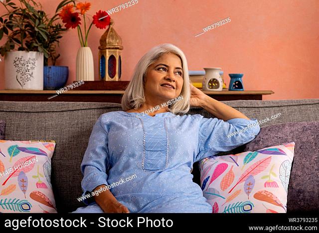 Portrait of old woman relaxing on sofa at home
