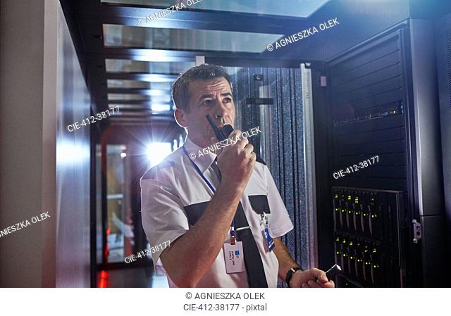 Male security guard using walkie-talkie in dark server room