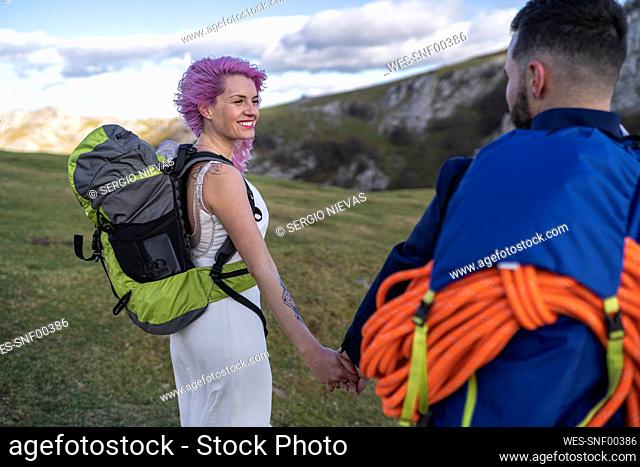 Bridal couple with climbing backpacks holding hands
