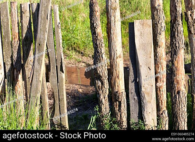 part of an old wooden fence, made of time-worn and sun-blown boards, some of which are broken, a close-up of a collapsing structure