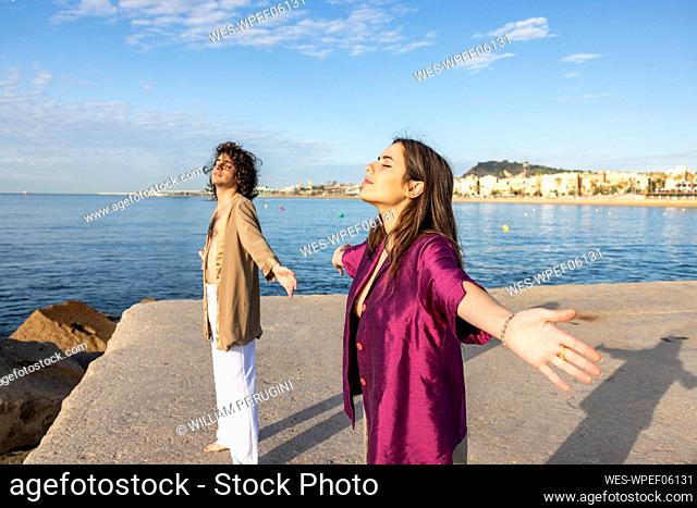 Couple with eyes closed standing on pier by sea