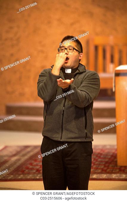 At a Laguna Niguel, CA, Catholic church, a Vietnamese American priest sticks out his tongue to demonstrate the correct way to eat a communion wafer to child...