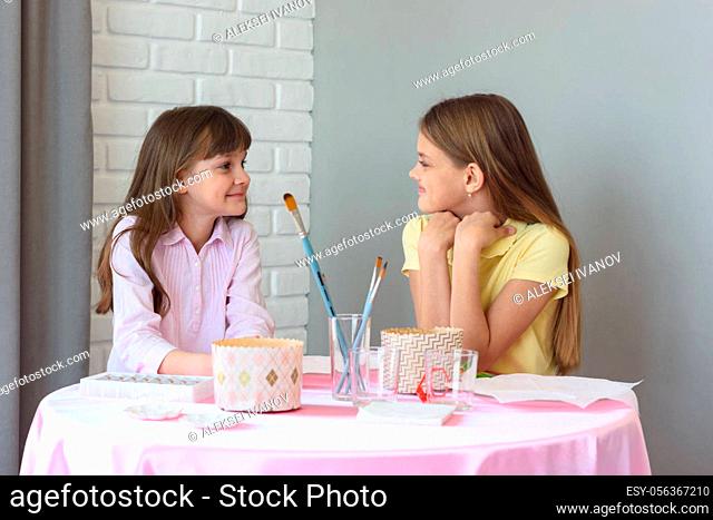Children sit at the table and wait for the start of the Easter celebration