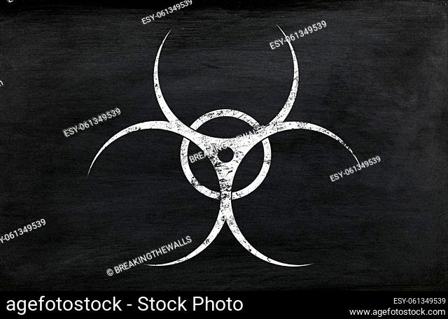 White chalk biohazard warning sign painted over grunge black chalkboard background with copy space