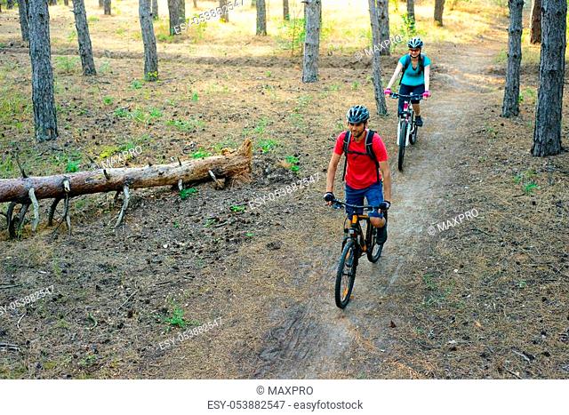 Young Couple Riding the Mountain Bikes in the Old Pine Forest. Adventure and Family Travel Concept