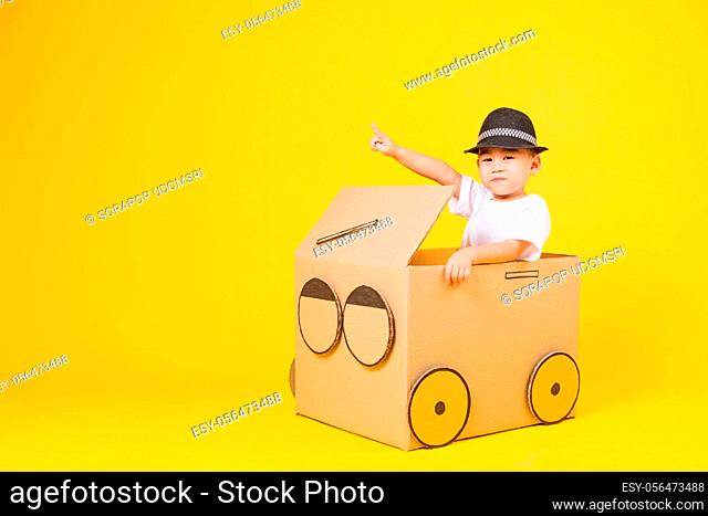 Portrait happy Asian cute little children boy smile so happy wearing white T-shirt driving car creative by cardboard and pointing finger