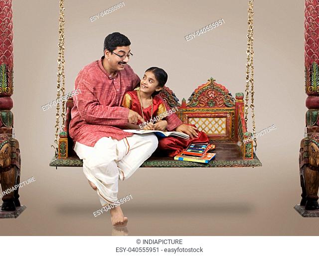South Indian man teaching his daughter