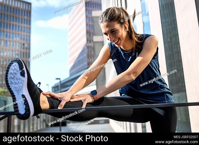 Smiling young woman exercising in front of building