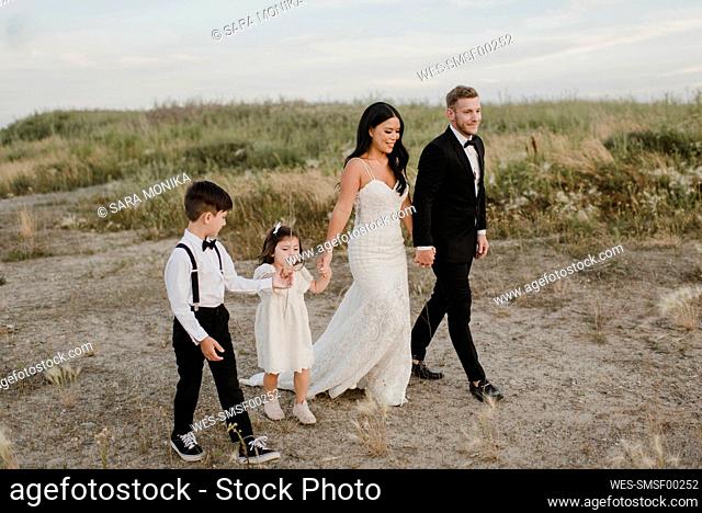 Parents with children wearing wedding dress while walking in field