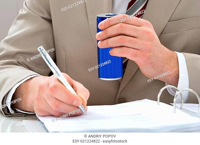 Close-up Of Businessman With Drink Can And Writing On Document