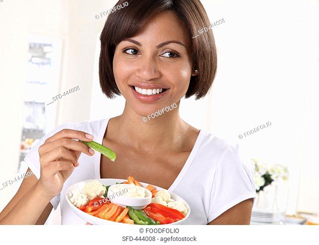 A woman eating crudites with a dip