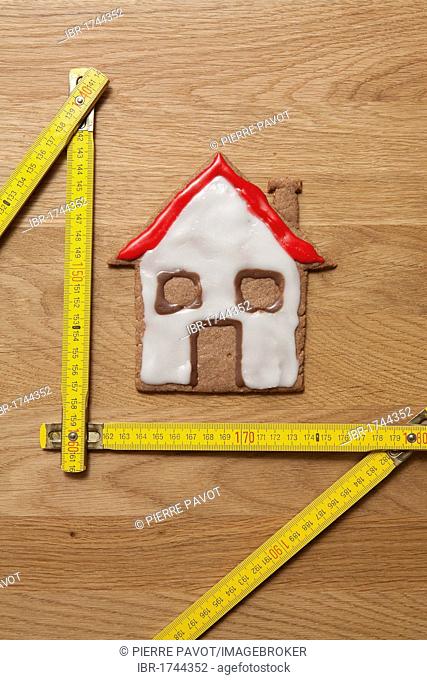 House biscuit with a measuring stick, symbolic image for home construction