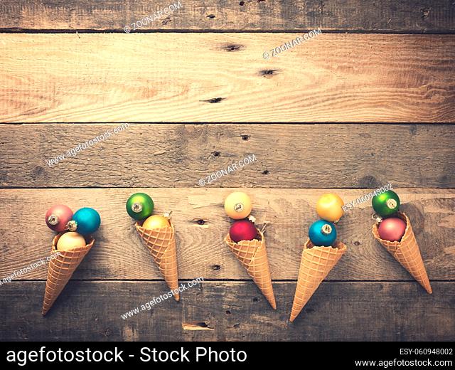 Vintage Christmas baubles in an ice cream cone decorated on a rustic wooden plank