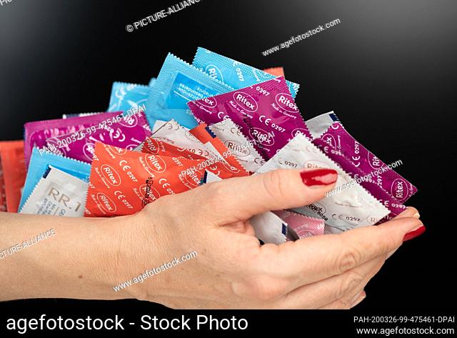 25 March 2020, North Rhine-Westphalia, Bielefeld: Condoms are held in hands. The strict contact requirements in the public due to the Corona crisis are...