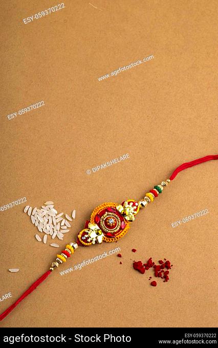 Raksha Bandhan background with an elegant Rakhi, Rice Grains and Kumkum. A traditional Indian wrist band which is a symbol of love between Brothers and Sisters