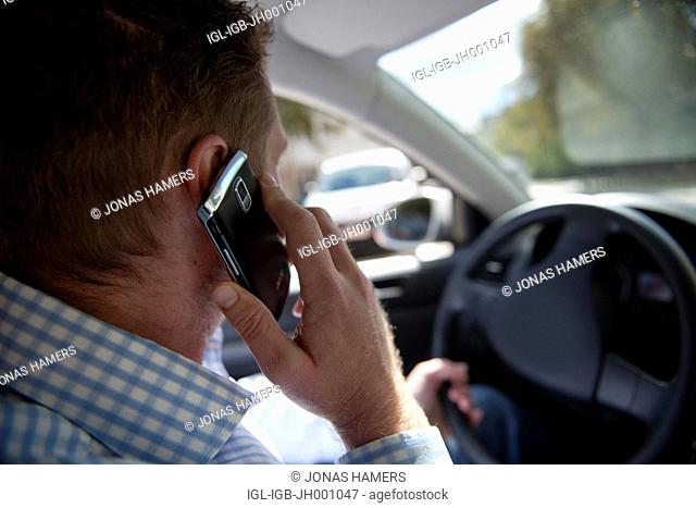 Man driving his car in the streets while having a conversation on the phone