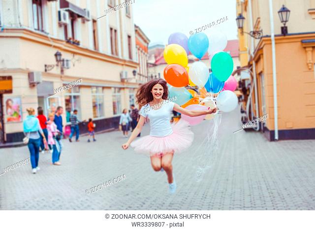 Teenage birthday. Pretty girl with big colorful balloons in the street of an old town