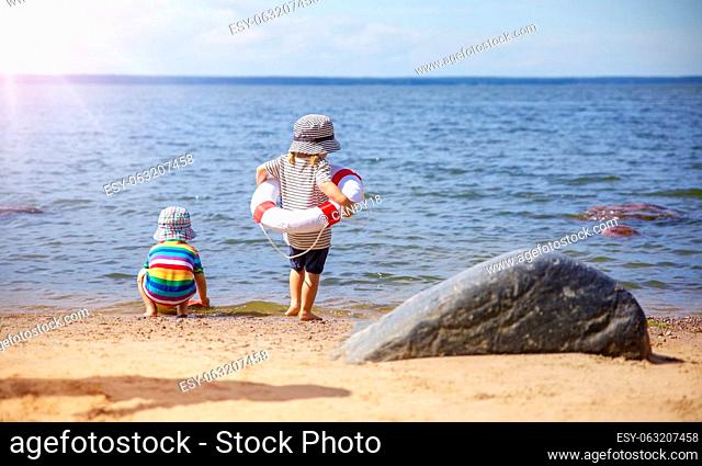 Girl and boy playing on the seashore with Lifebuoy. Concept of the family vacation, childhood and friendship
