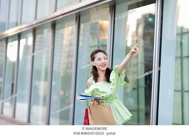 Young woman holding shopping bags and looking up with smile