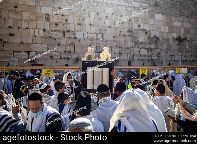 29 March 2021, ---, Jerusalem: Ultra-Orthodox Jews hold a Torah scroll as they recite the Birkat Cohanim or Priestly Blessing in front of the Western Wall