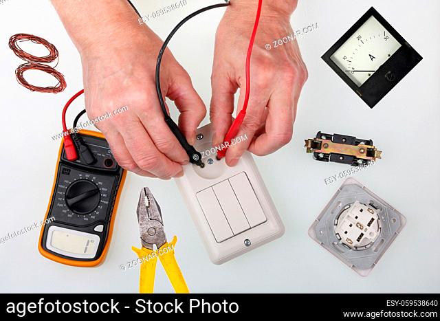An home master checks the isolation of the light switch using a multimeter