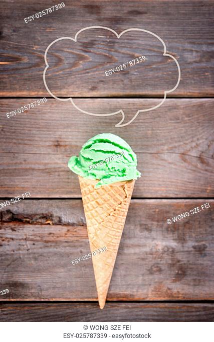Single green tea ice cream in a waffle cone over old rustic wooden vintage background with copy space on top