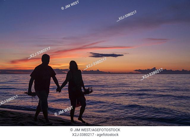 Union Pier, Michigan - A couple walks on the beach as the sun sets over Lake Michigan