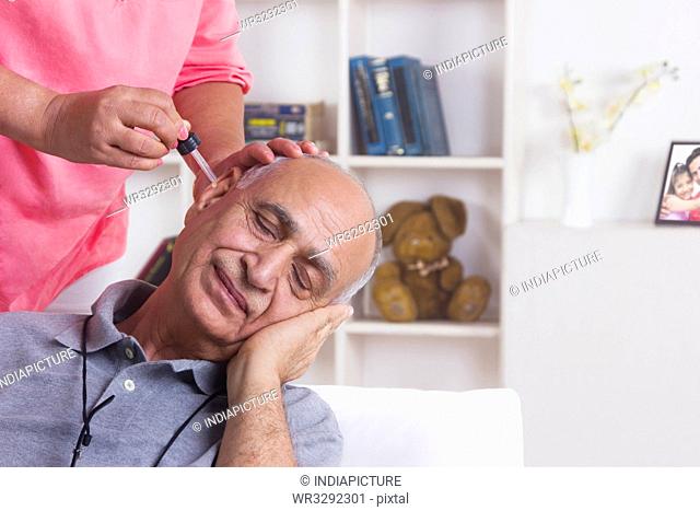 Old man getting ear drops put in