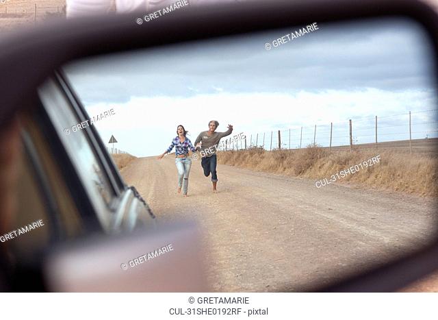 Couple running behind car
