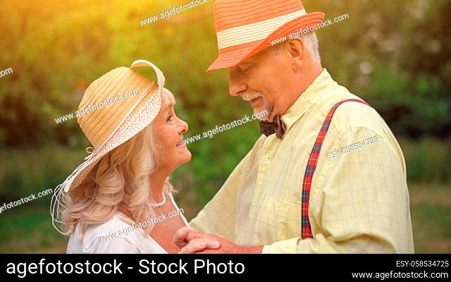 The portrait ot two elderly people dancing in the garden.They are looking at each other's eyes.They are still in love