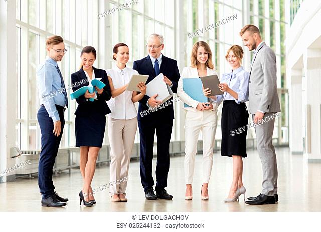 people, technology, work and corporate concept - business team with tablet pc computers and folders at office