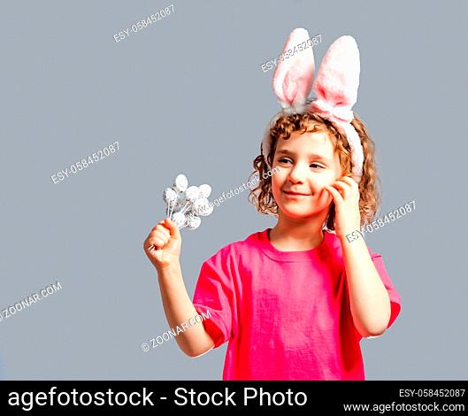 Portrait of a cute little girl wearing Easter bunny ears and holding small eggs