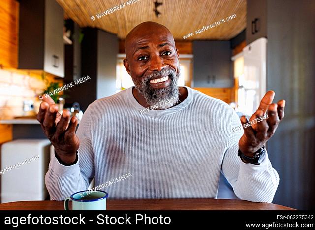 Happy african american man making video call gesturing to camera in log cabin