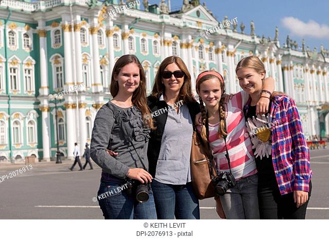 A mother and three daughters together in front of winter palace, st. petersburg russia