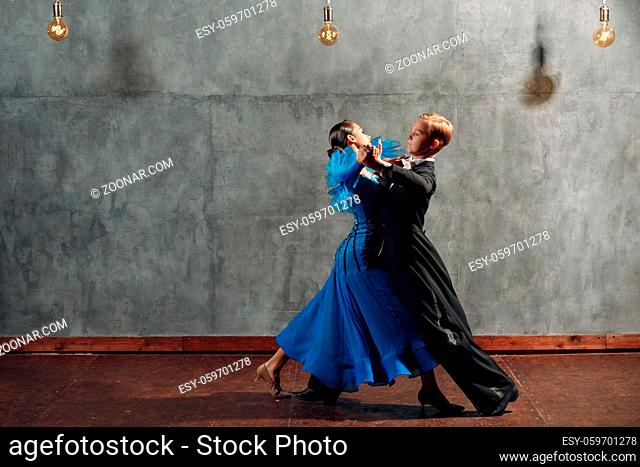 Young couple dancing slow waltz in ballroom