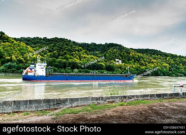 Jumieges, Normandy / France - 13 August 2019: blue and white freighter container ship traveling along the Seine River from Paris to the English Channel