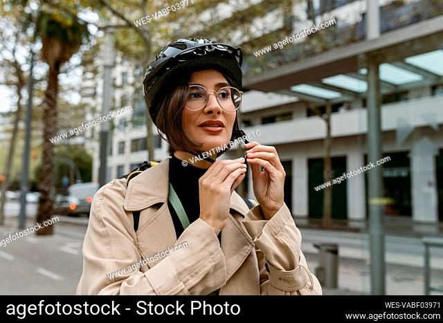 Woman wearing cycling helmet while standing at street in city