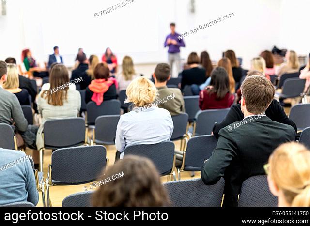 Business and entrepreneurship symposium. Speaker giving a talk at business meeting. Audience in the conference hall. Rear view of unrecognized participant in...